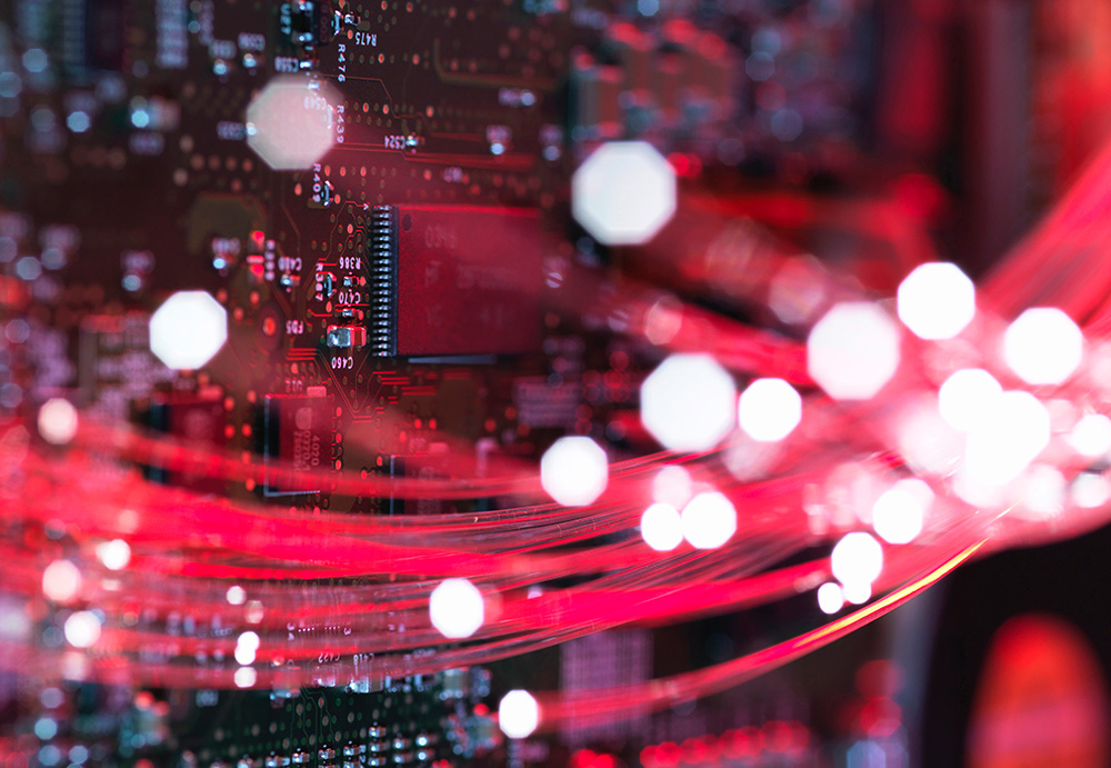 Red glowing fiber optic cables in front of a circuit board.
