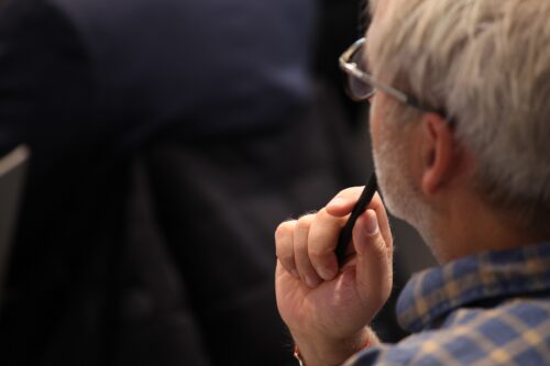 A participant closely listening to the lecturers while holding a pen in his hand