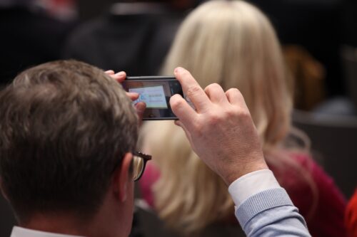 A participant taking a photo of the presentation with his smartphone